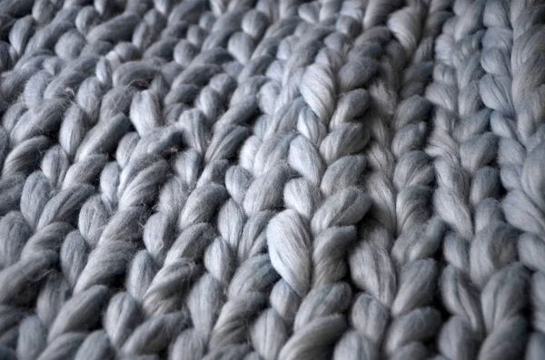 Merino wool handmade knitted large blanket, super chunky yarn, trendy concept. Close-up of knitted blanket, merino wool background
