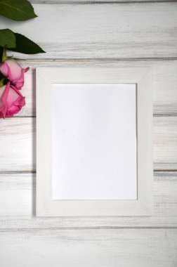 Pembe çarpıcı beyaz rustik ahşap zemin üzerine yükseldi. Uzay kopyalayın. Resim veya fotoğraf için beyaz çerçeve