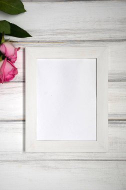 Pembe çarpıcı beyaz rustik ahşap zemin üzerine yükseldi. Uzay kopyalayın. Resim veya fotoğraf için beyaz çerçeve