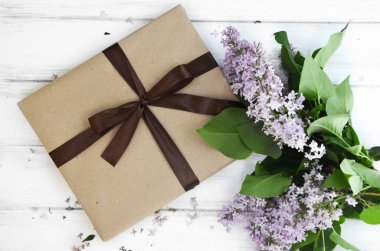 Hediyeler ve mavi ahşap zemin üzerine Eflatun çiçekler ile iki şenlikli hediye kutuları. Seçici odak. Metin için yer. Üstten Görünüm. Düz yatıyordu.