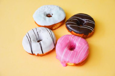 Çikolatalı buzlu, pembe sırlı ve bonibon donuts ve sarı zemin üzerine beyaz donat ile çeşitli börekler