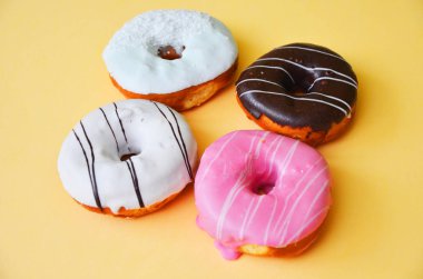 Çikolatalı buzlu, pembe sırlı ve bonibon donuts ve sarı zemin üzerine beyaz donat ile çeşitli börekler