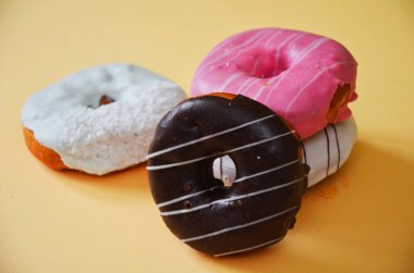 Çikolatalı buzlu, pembe sırlı ve bonibon donuts ile çeşitli çörekler. Çörek karışımı basit arka plan üzerinde