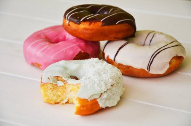 Renkli donut taş masada. Üstten görünüm. Çikolatalı buzlu, pembe sırlı ve bonibon donuts ile çeşitli börekler.