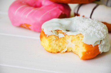 Renkli donut taş masada. Üstten görünüm. Çikolatalı buzlu, pembe sırlı ve bonibon donuts ile çeşitli börekler.