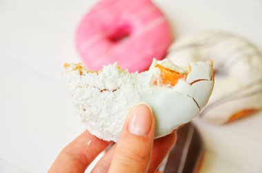 Renkli donut taş masada. Üstten görünüm. Çikolatalı buzlu, pembe sırlı ve bonibon donuts ile çeşitli börekler.