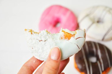 Renkli donut taş masada. Üstten görünüm. Çikolatalı buzlu, pembe sırlı ve bonibon donuts ile çeşitli börekler.