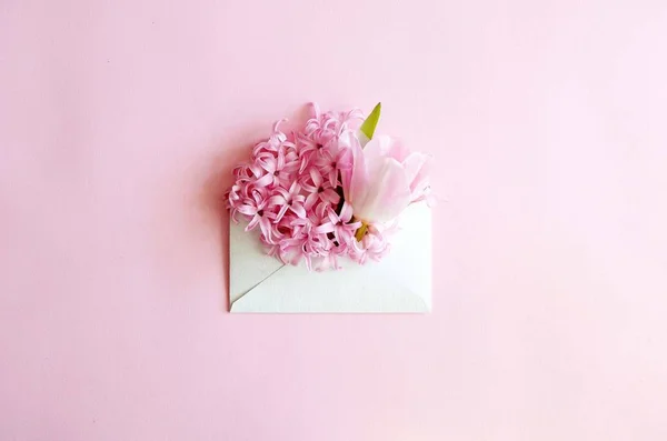 Vintage vierkante kaart met close-up geopende ambachtelijke papier envelop gevuld met lente bloesem paars lila bloemen. Bovenaanzicht, plat lag. — Stockfoto