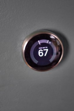 Mavi duvarda termostat var. Yansıma dış halka için altın yonga verir. Mavi merkez ısıtma ve soğutma akıllı yuva termostatı