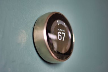 Mavi duvarda termostat var. Yansıma dış halka için altın yonga verir. Mavi merkez ısıtma ve soğutma akıllı yuva termostatı