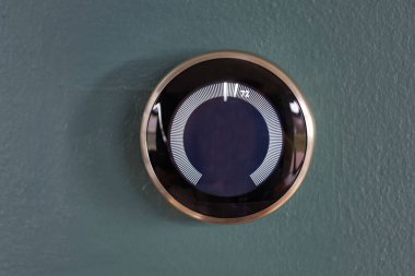 Mavi bir duvara izole edilmiş merkezi bilgisi olmayan akıllı ev termostatı veya yuvası