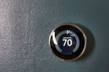 Mavi duvarda 70 derece termostat izole edilmiş. Yuva termostatı enerji tasarrufu teknolojisi. Isıtma ve soğutma aygıtı.