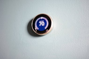 Akıllı ev termostatı mavi duvarda izole edilmiş. Kopya ve yazıya yer var. Yeşil teknoloji ısıtma ve soğutma