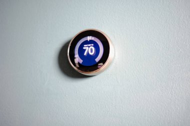 smart home thermostat isolated on blue wall. Room for copy and writing. Green tech heating and cooling clipart