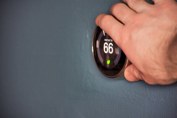 Hand adjusting temperature on electric thermostat