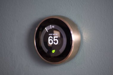 Smart home thermostat displaying temperature at an energy saving 65 degrees. Nest house temperature clipart