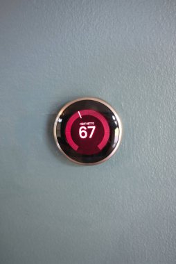 Isı modunda kırmızı merkezli akıllı ev termostatı. Enerjiyi evi ısıtmaktan kurtarıyorum. Mavi duvarda izole edilmiş ürün