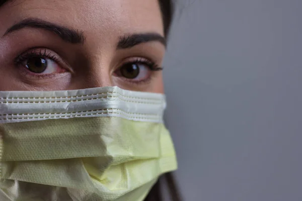 Gri arka planda maske takan kadın sağlık görevlisi izole edilmiş. Kopya veya metin için boşluk. Steteskop ve beyaz önlük giyiyor..
