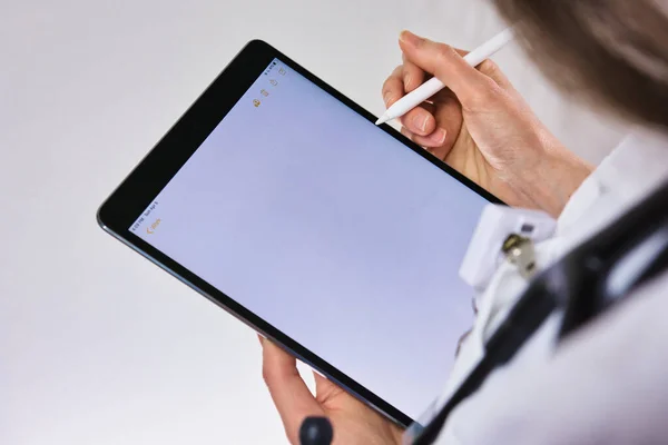 Healthcare worker using tablet to conduct healthcare. doctor or nurse practitioner Writing prescription. Physician assistant wearing stethoscope