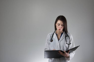 Female healthcare professional making note in patient's charge isolated on grey background clipart