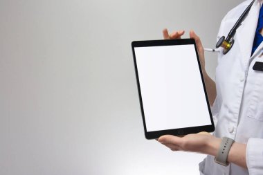 Medical worker with tablet held toward camera. Blank for adding copy or text. Stethoscope and white coat visible on grey background clipart