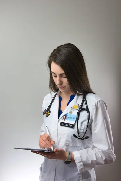 Dark haired woman making note in patient chart. Female healthcare worker with stethoscope making notes