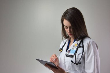 woman making note on tablet for patient care in hospital. Healthcare female, could be MD, PA, or NP clipart