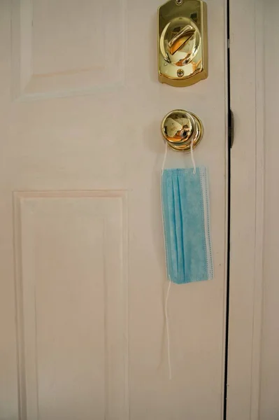 Mask hanging on door with broken string. Indicating an end to coronavirus pandemic. Facemask for protecting during covid-19
