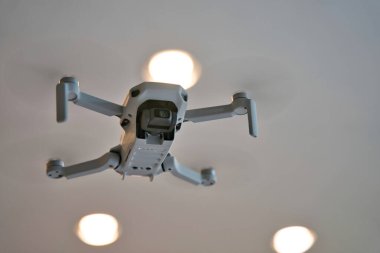 Arka planda tavan olan kapalı alanda uçan bir dron. İHA 'nın altında evin içinde uçuyor..