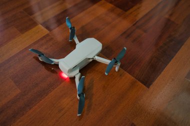 Drone ahşap zeminde oturuyor ve şarjı bitmiş. İç mekan insansız hava aracı.