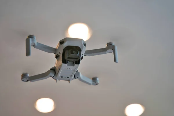 Arka planda tavan olan kapalı alanda uçan bir dron. İHA 'nın altında evin içinde uçuyor..