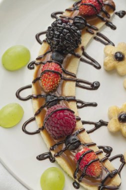 Bir dilim muz çilek ve çikolata tepesi ile gelen tatlı