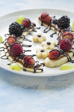 Bir dilim muz çilek ve çikolata tepesi ile gelen tatlı