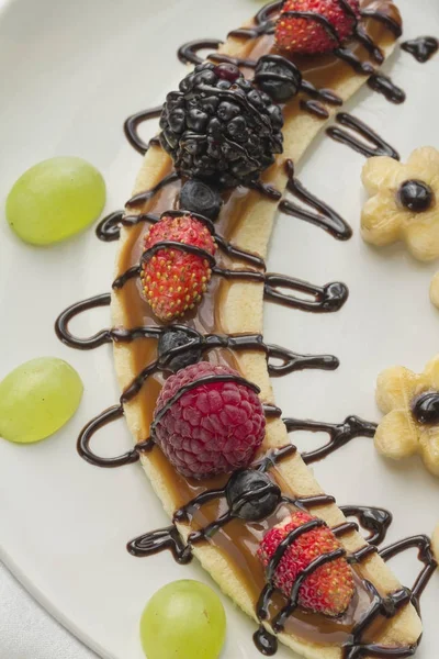 Bir dilim muz çilek ve çikolata tepesi ile gelen tatlı