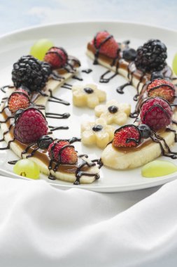 Bir dilim muz çilek ve çikolata tepesi ile gelen tatlı