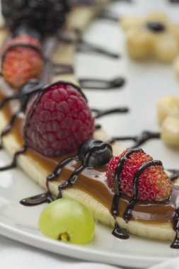 Bir dilim muz çilek ve çikolata tepesi ile gelen tatlı