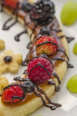 Bir dilim muz çilek ve çikolata tepesi ile gelen tatlı