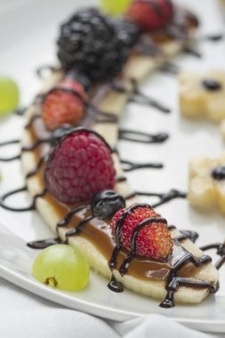 Bir dilim muz çilek ve çikolata tepesi ile gelen tatlı