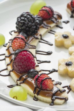 Bir dilim muz çilek ve çikolata tepesi ile gelen tatlı