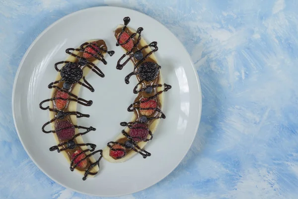 Bir dilim muz çilek ve çikolata tepesi ile gelen tatlı