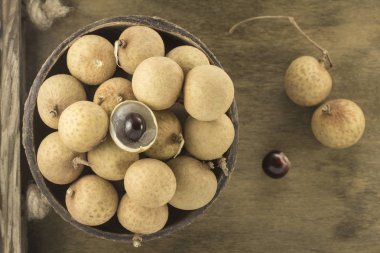 Ahşap kontrplak bir arka plan üzerinde seramik bir kasede Longan 