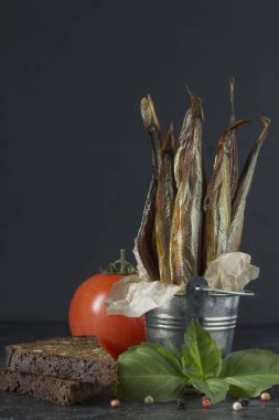 Karanlık bir backgr dekoratif bir kova capelin soğuk füme balık