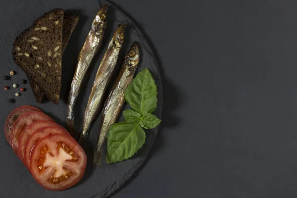 Siyah backgr üzerinde yuvarlak kayrak tabakta capelin balık soğuk füme