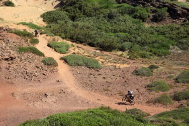 Cala Pregonda, Menorca / Spain - June 23, 2016: A cyclist near Cala Pregonda Biosphere Reserve area view, Menorca, Balearic Islands, Spain  clipart