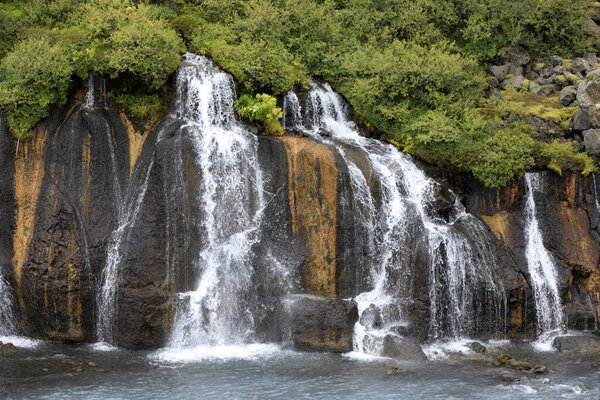 Hraunfossar / Iceland - August 15, 2017: Hraunfossar waterfalls formed by rivulets streaming out of the Hallmundarhraun lava field formed by the eruption of a volcano lying under the glacier Langjokul., Iceland, Europe