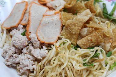 Kırmızı domuz eti, kıyma, soğan ve kızarmış Wonton çarşafı ve Çin mutfağı karışımında kurutulmuş yumurtalı erişteyi yakından izleyin.