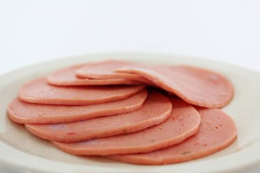 Haşlanmış jambon ya da salam dilimleri beyaz tabakta.