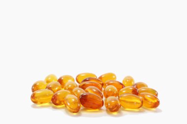 beyaz zemin üzerinde morina karaciğeri yağı kapsülleri