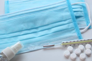Tıbbi koruyucu maske, cıva termometre, ilaç hapları ve alkol spreyi, karantina konsepti, COVID-19, koronavirüs, tedavi önleme.