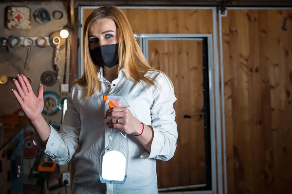 a girl in a virus mask sprays antiseptic